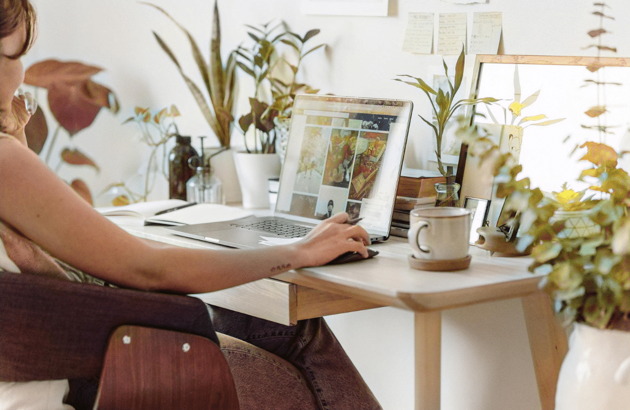 Femme travaillant à domicile avec un ordinateur portable sur un bureau moderne entouré de plantes d'intérieur. Un environnement de bureau ergonomique avec une tasse de café, des livres et des plantes vertes apportant une touche de nature à l'espace de travail. Ambiance sereine et productive dans un bureau à domicileCour intérieure moderne d'un bâtiment de bureaux avec des arbres verts plantés dans des pots métalliques brillants. Architecture contemporaine avec grandes fenêtres et espace de travail lumineux. Ambiance professionnelle et écologique dans un cadre urbain.