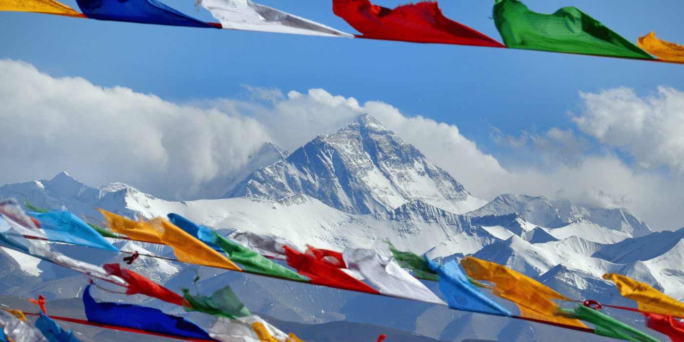 Vue spectaculaire de l'Everest avec des drapeaux de prière colorés au premier plan. Parfait pour illustrer la majesté de la plus haute montagne du monde et la culture tibétaine, cette image capture l'essence de l'aventure en haute montagne et du voyage spirituel.