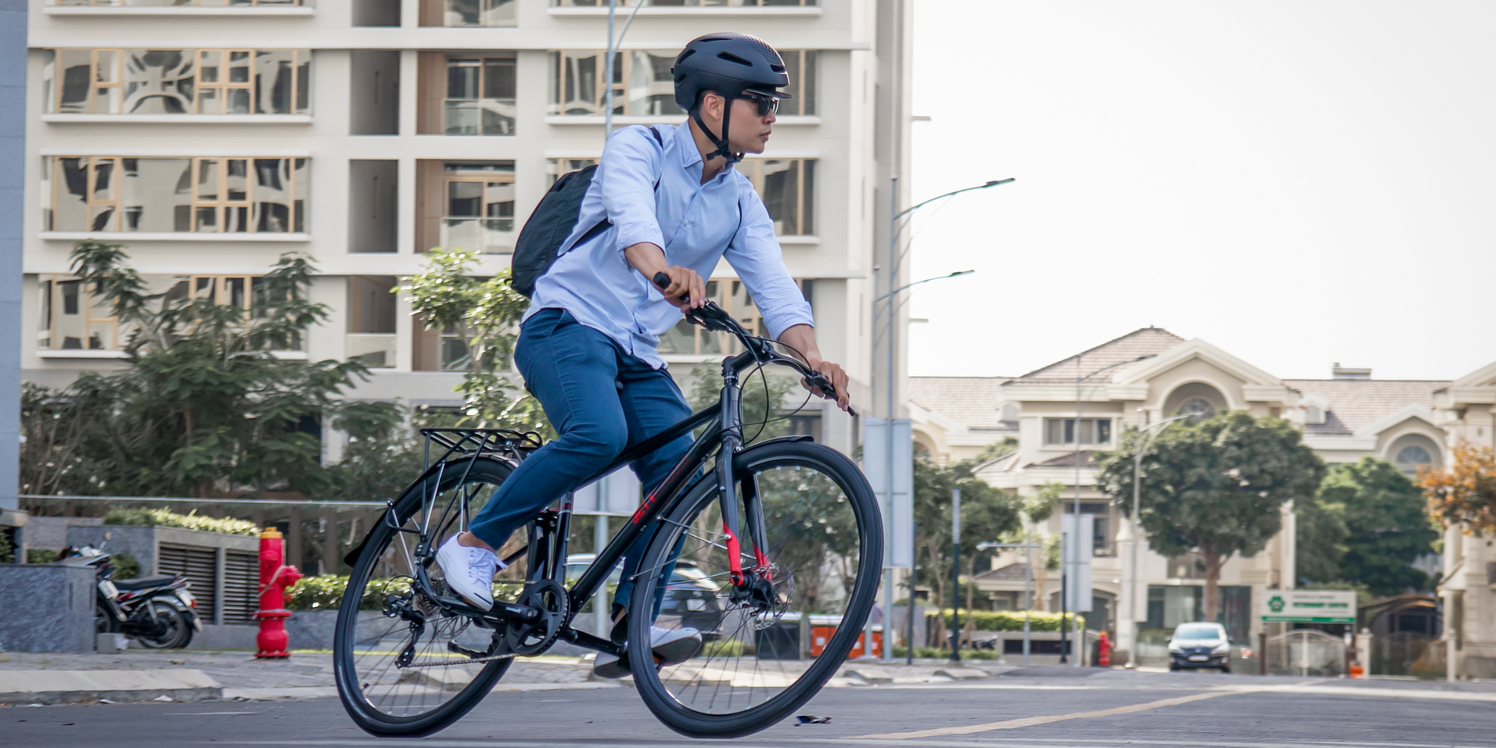 Homme à vélo dans un environnement urbain moderne, un exemple parfait de l’adoption des mobilités douces pour des trajets quotidiens responsables.