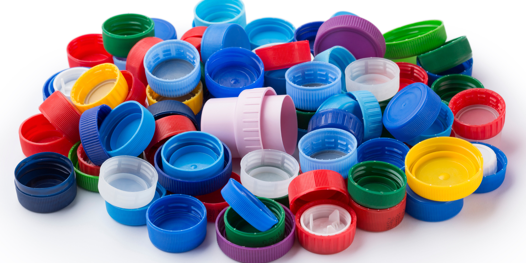 Collection de bouchons en plastique multicolores posés sur fond blanc. Idéal pour le recyclage, l'art créatif ou l'illustration de la pollution plastique.
