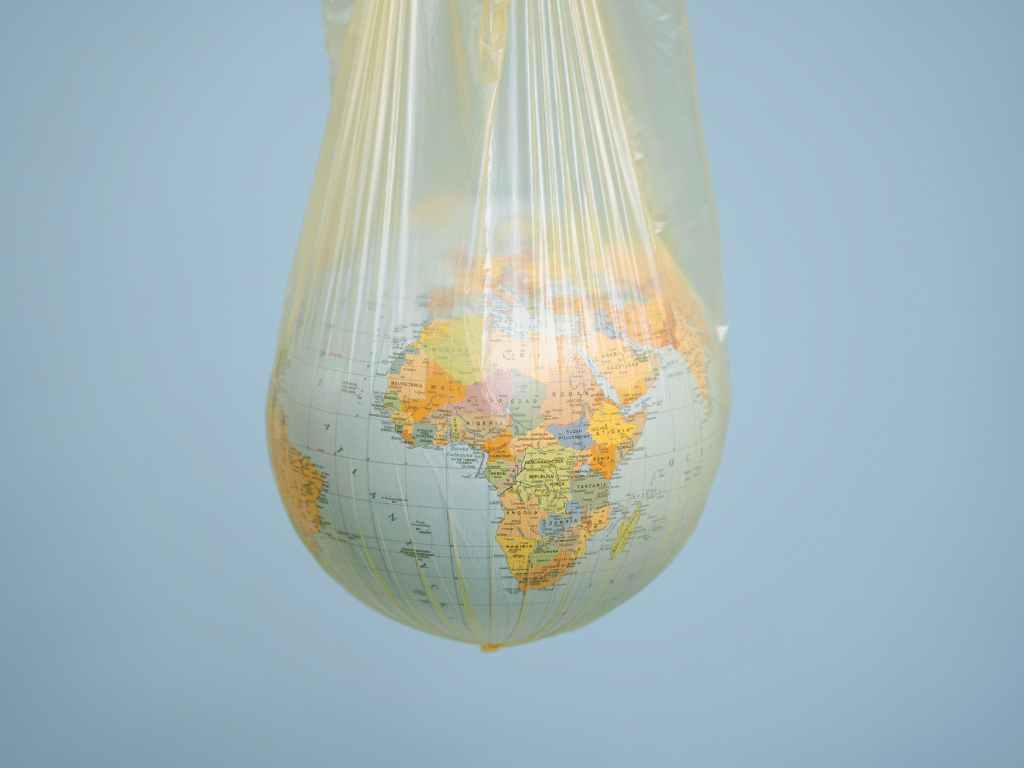 Planète Terre représentée dans un sac plastique suspendu, métaphore de la pollution plastique.