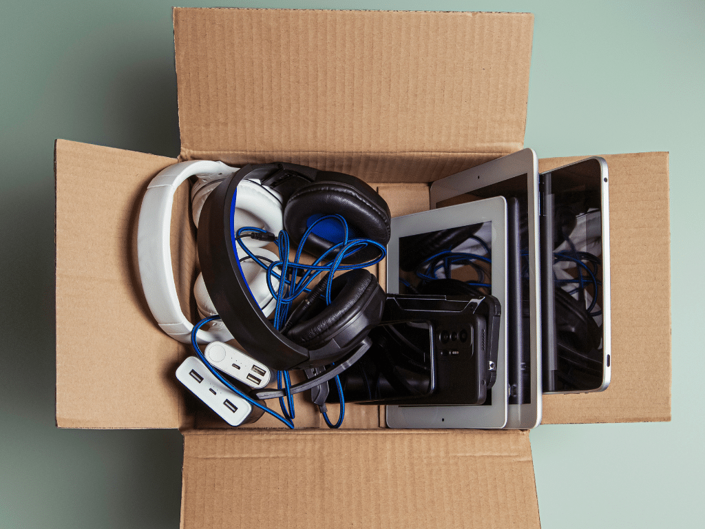 Collecte de matériel électronique pour recyclerie Carton ouvert rempli de câbles, écouteurs et matériel informatique usagé destiné au recyclage et au réemploi