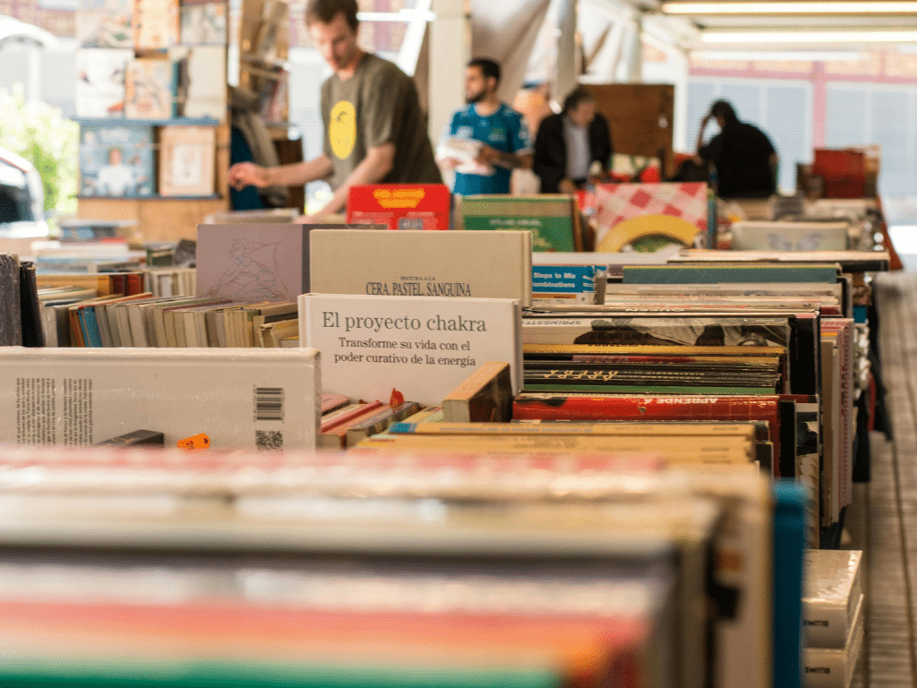 Vente d’objets de seconde main. Allée intérieure d’une ressourcerie ou marché aux puces avec des caisses remplies de vinyles et de livres d’occasion