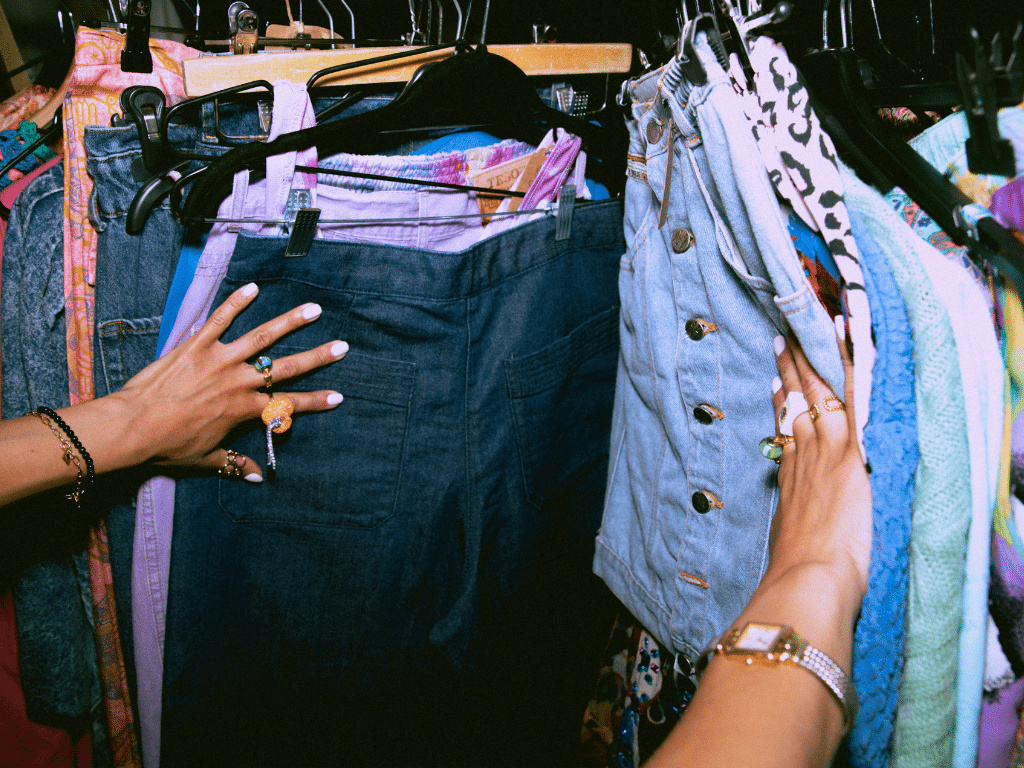 18.	Personne examinant des vêtements colorés suspendus sur un portant dans un magasin ou un marché.