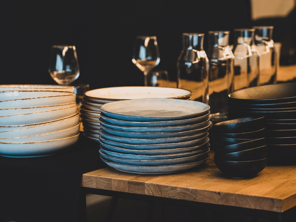 19.	Table de restaurant avec piles d’assiettes et verres à vin soigneusement disposés.