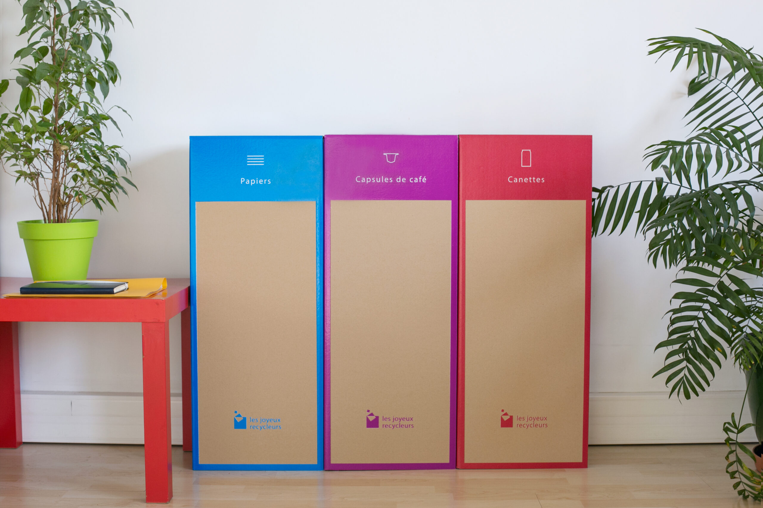 Rangée de bacs de tri sélectif aux couleurs vives, dont un pour les capsules de café.