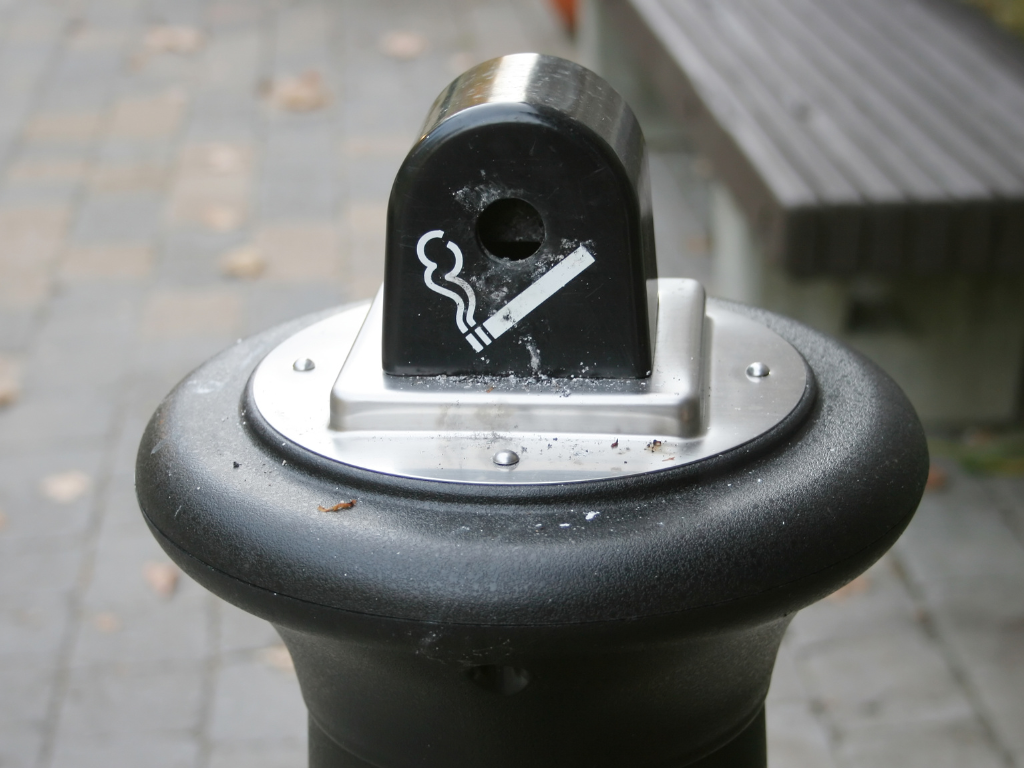 Cendrier public en métal installé sur un trottoir pour collecter les mégots de cigarettes.