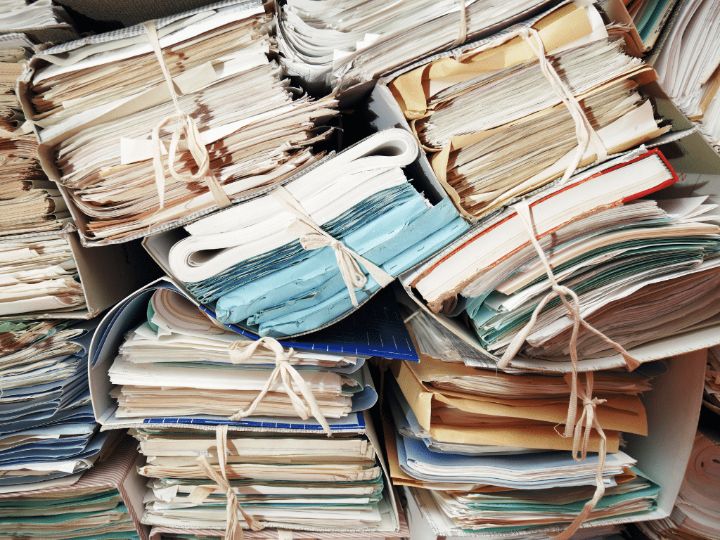 Tas de vieux dossiers et de papiers ficelés, empilés les uns sur les autres, illustrant le tri et le recyclage d’archives papier
