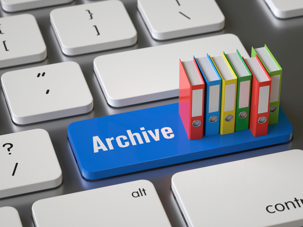 Désarchiver, trier, recycler _ le débarras d’entreprise sans prise de tête Clavier d’ordinateur avec une touche bleue sur laquelle est écrit « Archive », entourée de petites icônes de dossiers colorés représentant le classement et l’archivage numérique