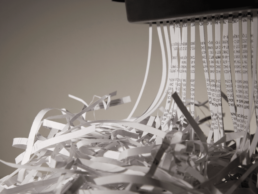Grosse pile de papiers en train d’être broyés par une déchiqueteuse, symbolisant la destruction sécurisée et le recyclage des documents
