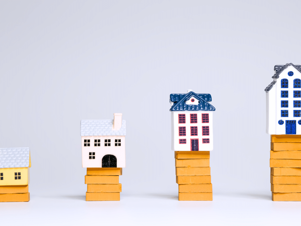 Petites figurines représentant des maisons et des immeubles posées sur des blocs jaunes de tailles différentes, symbolisant la hiérarchie entre TPE, PME et grands groupes.