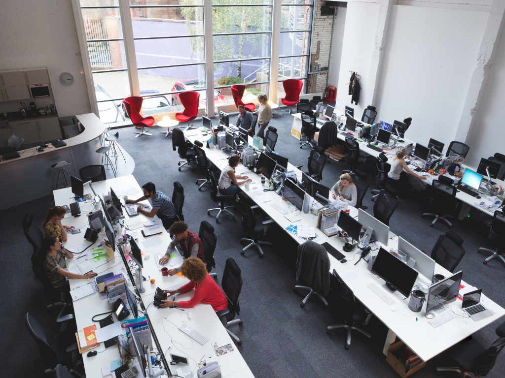 Vue d’un open space moderne avec plusieurs collaborateurs travaillant sur ordinateurs, représentant la vie en entreprise.