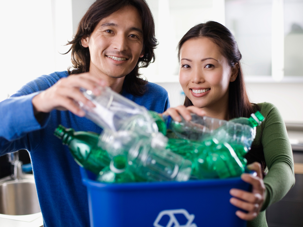 Employés triant des bouteilles plastiques dans un bac de recyclage, illustrant les bonnes pratiques environnementales au travail.