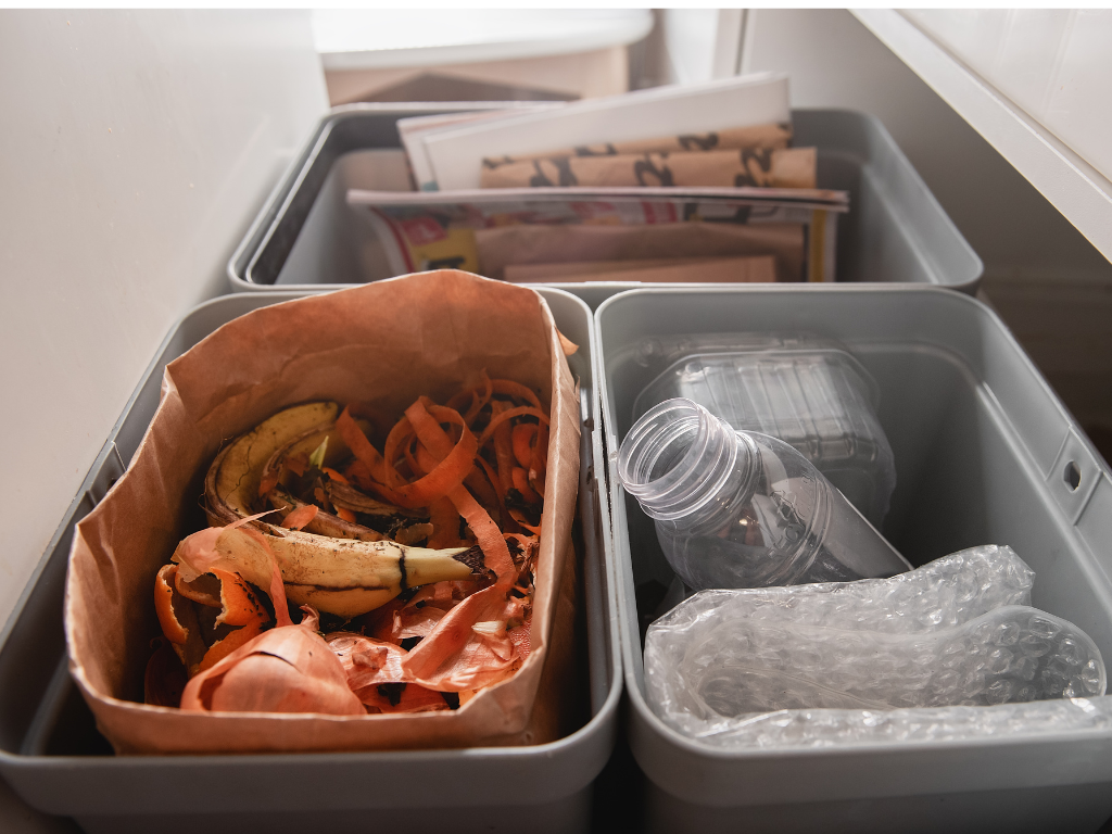 Plusieurs bacs de tri domestiques séparant plastiques, papiers et biodéchets, symbolisant la pratique du tri sélectif à la maison