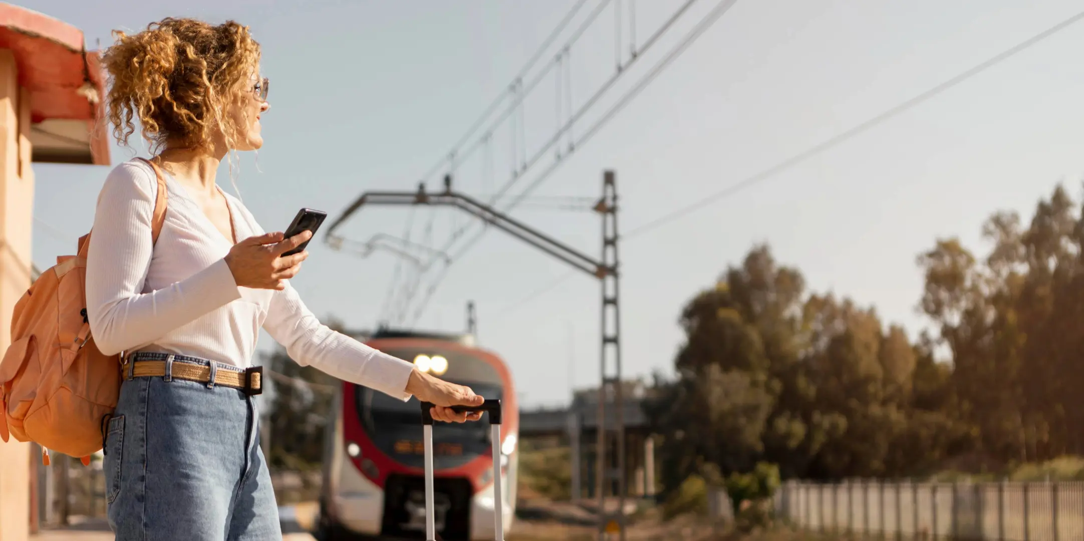 Femme attendant un train avec une valise, illustrant l’usage des transports en commun pour réduire son empreinte carbone