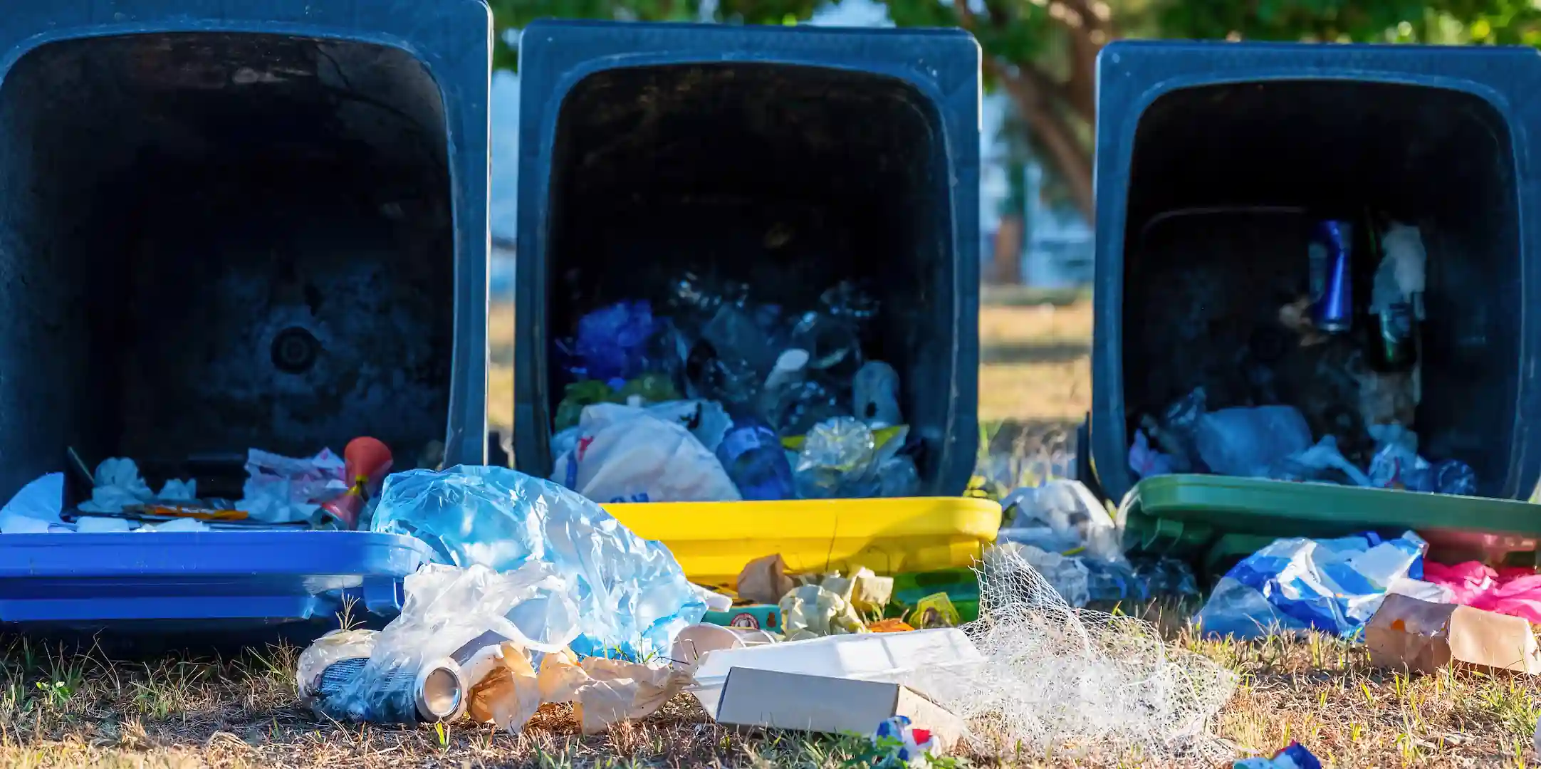 Poubelles de tri renversées avec des déchets mélangés au sol, sacs et emballages